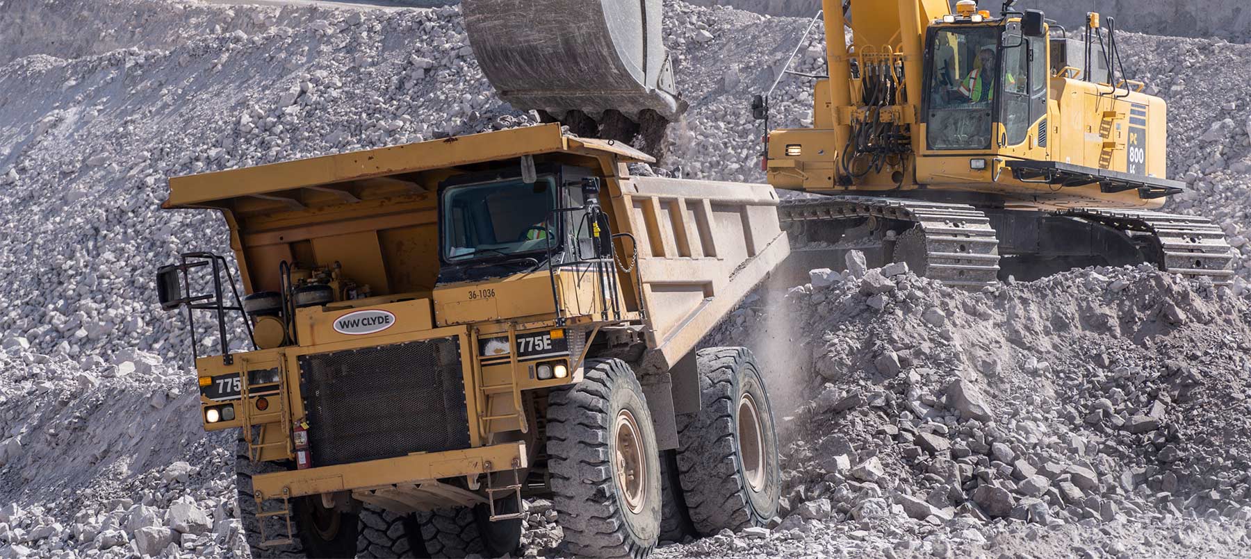 Track Hoe loading overburden into haul truck at mass excavation.