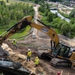 Placing concrete to hold newly installed pipe into place.