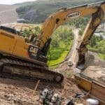 Setting concrete anchor with a track hoe as a track loader brings concrete up the mountain side next to the Jordanelle Dam.